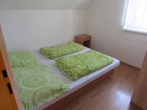 2 Betten in einem kleinen Zimmer mit grüner Bettwäsche und Kissen in der Unterkunft Apartmány Bobrovnik in Liptovská Sielnica