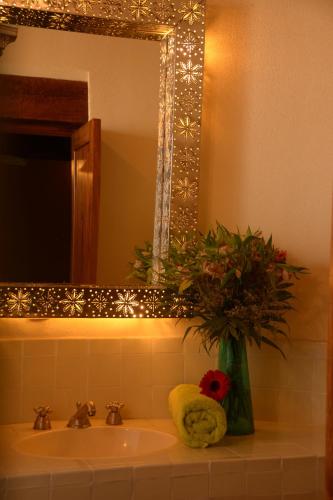 a bathroom sink with a vase of flowers and a mirror at Hotel Chocolate Suites in Guanajuato
