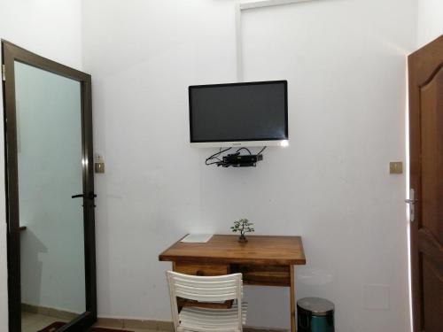a room with a table and a tv on a wall at Marys Guest House in Lomé