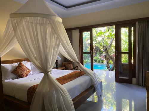 a bedroom with a canopy bed and a pool at vishaka ubud villa in Ubud