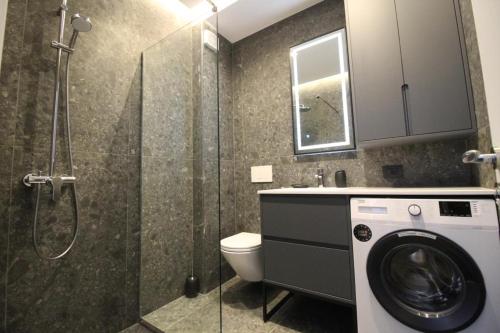 ein Bad mit einer Dusche und einer Waschmaschine in der Unterkunft Magnifique Apartments in Sarandë