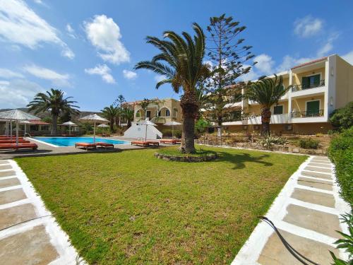 a resort yard with a palm tree and a swimming pool at Alex in Karpathos Town