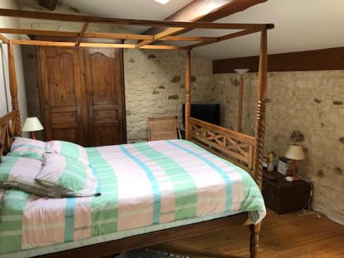 a bedroom with a wooden bed with a striped comforter at Maison ancienne avec piscine au milieu des vignes 
