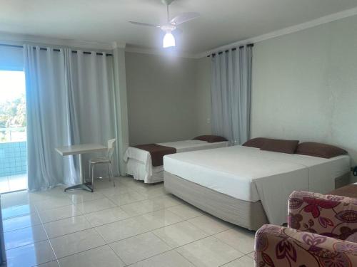 a bedroom with two beds and a table and a desk at Hotel Adventure São Luís in São Luís