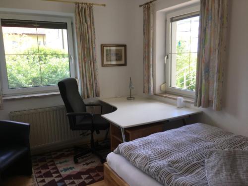 a bedroom with a desk and a bed and two windows at Gemütliche und geräumige Unterkunft, Nähe Linz in Luftenberg an der Donau