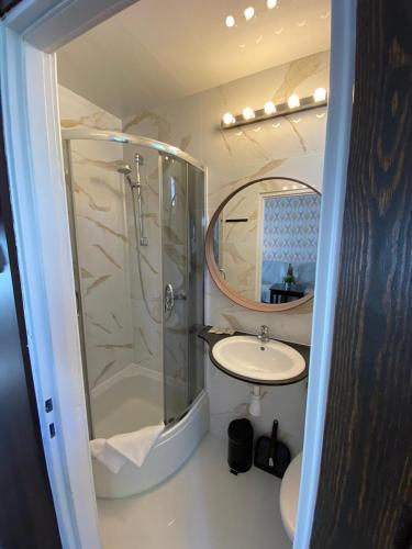 a bathroom with a shower and a sink and a mirror at Oaza Resort in Stegna
