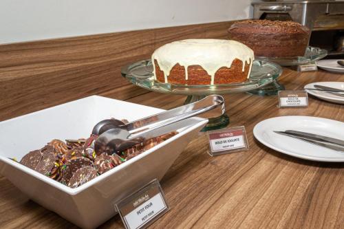 a table with a cake and a plate of desserts at Hotel Malibu Inn Campinas in Campinas