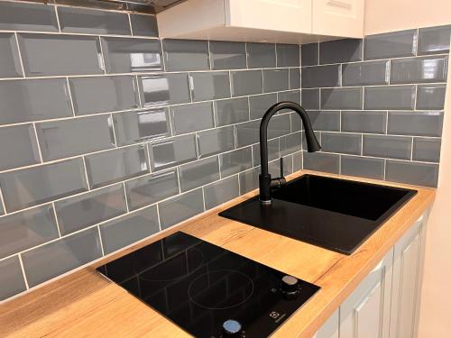 a kitchen with a black sink and gray tiles at Stella Apartments in Kaštela