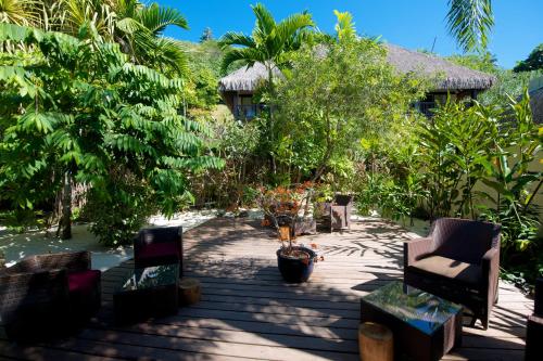 a patio with chairs and trees in front of a house at Maitai Bora Bora in Bora Bora
