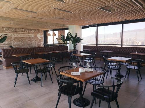 a restaurant with wooden tables and chairs and windows at Hotel Alto Antofagasta in Antofagasta