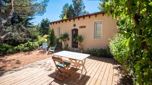 una terraza de madera con mesa y sillas frente a una casa en Le Pavillon - Les Lodges de Praly en Les Ollières-sur-Eyrieux