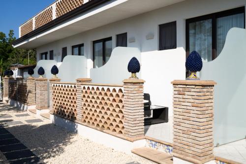 a white house with brick pillars and windows at Paradise Sicily Rooms in Calatabiano