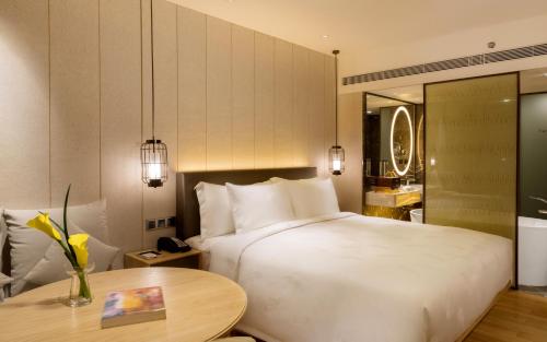 a bedroom with a large white bed and a table at The Garden Hotel Guangzhou - Discover 26 cultural treasures with hotel Golden Tour Guide in Guangzhou