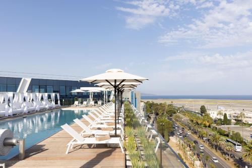 a pool with chairs and umbrellas on top of a building at Sheraton Nice Airport in Nice