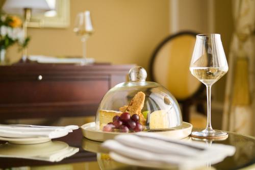 a table with a plate of cheese and grapes and a glass container at Castlemartyr Resort Hotel in Castlemartyr