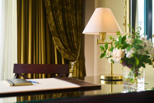 a table with a lamp and a vase of flowers on it at Castlemartyr Resort Hotel in Castlemartyr