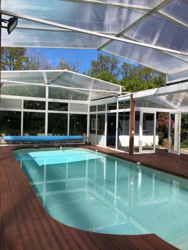 une piscine extérieure avec un auvent et une grande piscine dans l'établissement villa Simon, à Auberville