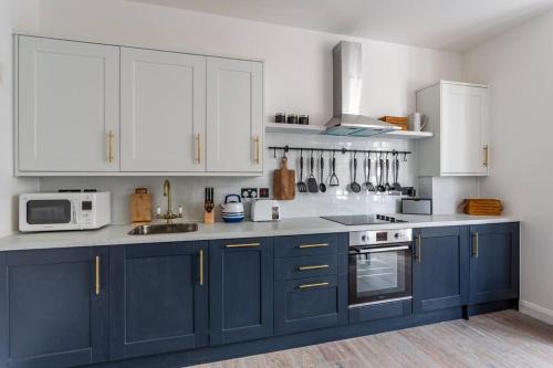 a kitchen with blue cabinets and white appliances at Shape of Water in Southend-on-Sea