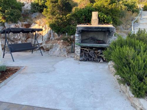 a stone fireplace with a bench and an umbrella at Alleinstehendes Haus am Meer Robinson in Tkon