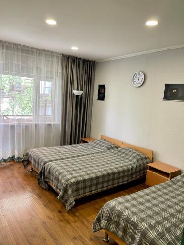 a room with two beds and a clock on the wall at Hotel Crocus in Bosteri