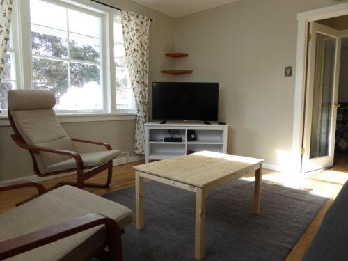 a living room with a tv and a table and a chair at Banff Beaver Cabins in Banff