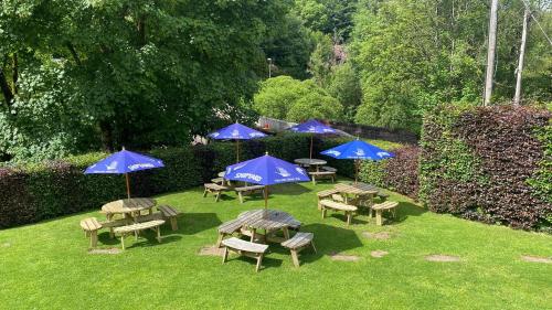 a group of tables and chairs with blue umbrellas at Bridge of Cally Hotel in Blairgowrie