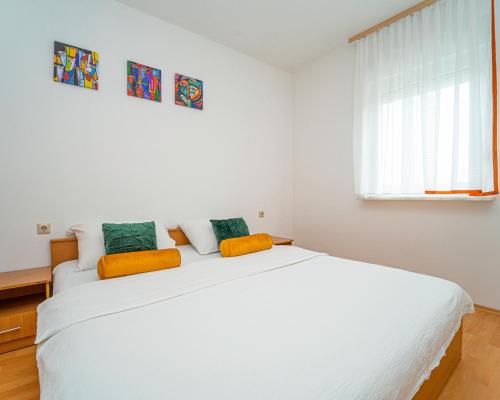 a white bedroom with a large white bed and a window at Apartments Baresic in Medulin