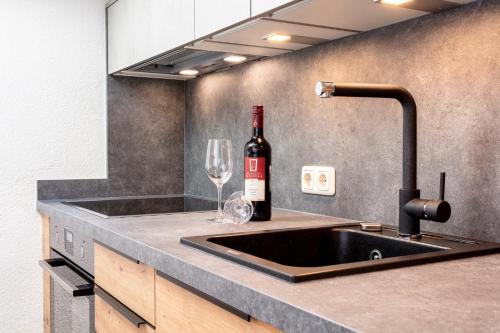 a kitchen sink with a bottle of wine and a wine glass at Haus Bergliebe in Maria Alm am Steinernen Meer