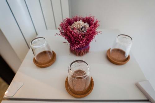 a table with three glasses and a flower on it at Palazzo ReSilente- B&B dell'Infopoint in Castelnuovo Cilento