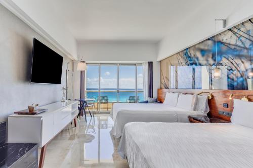 a hotel room with two beds and a television at Live Aqua Beach Resort Cancun in Cancún