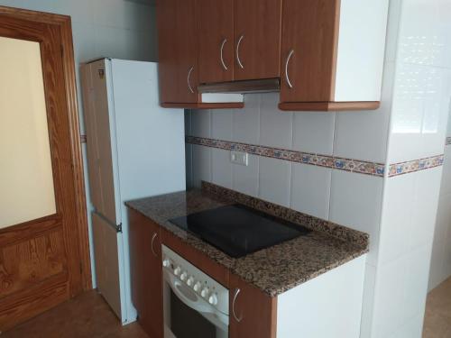 a kitchen with a stove top oven next to a refrigerator at Àtic Montsià - Àtic amb chill-out in Amposta