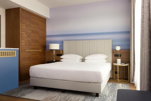ニースにあるSheraton Nice Airportのベッドルーム1室(白いベッド1台、青い壁付)