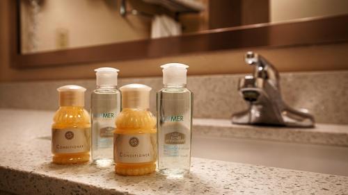 three bottles of soap sitting on a bathroom sink at Sky Point Hotel & Suites - Atlanta Airport in Atlanta