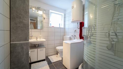 a white bathroom with a sink and a toilet at Holiday Home Kokot in Ravna Gora