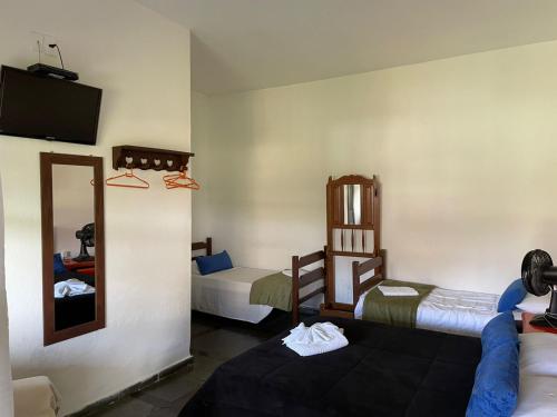 a small room with two beds and a mirror at Pousada Minas Goiás in Tiradentes