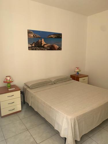 蘭佩杜薩的住宿－Lopadusa trilo 2，卧室配有1张床和2张桌子,墙上挂着1张照片