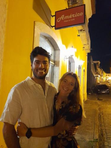 a man and a woman standing in front of a yellow building at Americo Pousada e Hostel in São Luís