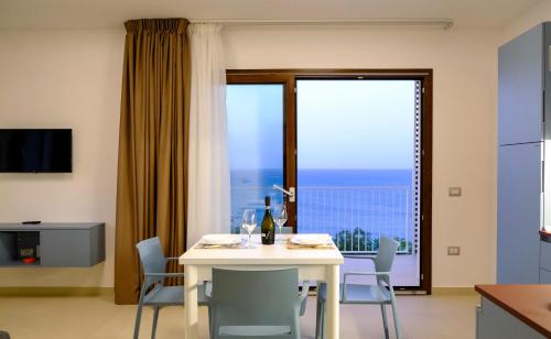 ein Esszimmer mit einem weißen Tisch und Stühlen sowie einem Fenster in der Unterkunft SOL Y MAR Camere e Appartamenti in Castellammare del Golfo