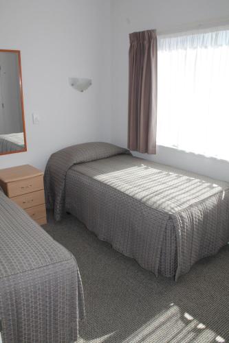 a bedroom with two beds and a mirror and a window at Riverview Motel in Whanganui