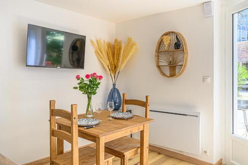 une table à manger avec deux chaises et une télévision dans l'établissement LA CARLITA - Studio Proche gare Vannes avec parking, à Vannes