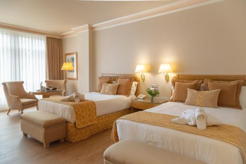 サンティアゴ・デ・コンポステーラにあるグラン ホテル ロス アベトスのベッド2台とデスクが備わるホテルルームです。