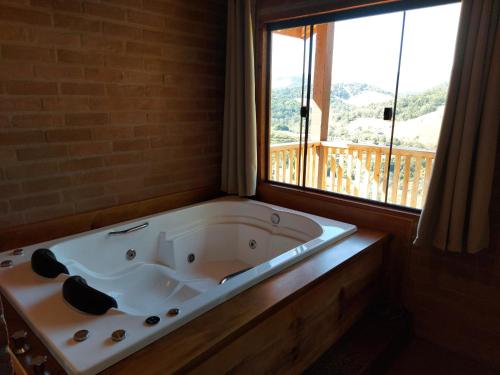 a bath tub in a room with a large window at Chalés Santa Luzia in Santo Antônio do Pinhal
