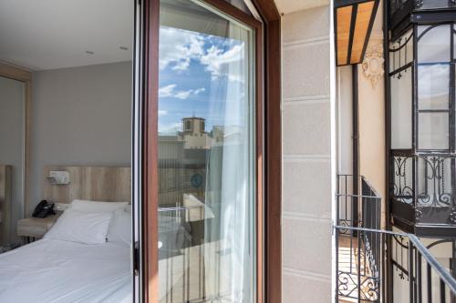 a room with a bed and a balcony with a window at DWO Ábaster in Soria