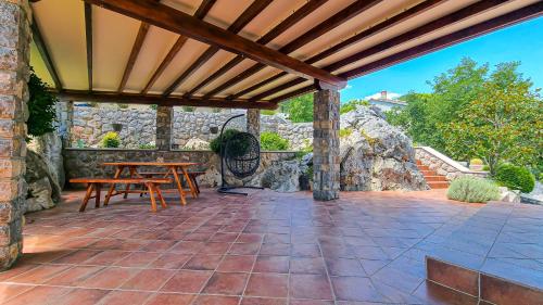 a patio with a table and a stone wall at Apt - Villa Sambije with swimming pool, Dobrec - Opatija in Dobreć