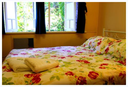 a bed with a floral bedspread and two windows at Coral Lodge Bed and Breakfast Inn in Townsville