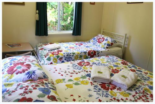 two beds in a room with floral sheets at Coral Lodge Bed and Breakfast Inn in Townsville