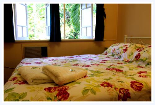 a bed with a floral bedspread and two windows at Coral Lodge Bed and Breakfast Inn in Townsville