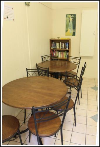 four tables and chairs in a room with a book shelf at Coral Lodge Bed and Breakfast Inn in Townsville