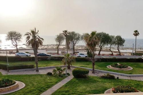 uma vista para um parque com palmeiras e o oceano em First Sea Line Apartment, Acre - amazing coastal view in heart of Akko em Acre