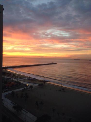 a sunset over the ocean with a beach at APARTAMENT BEACH FORTALEZA in Fortaleza